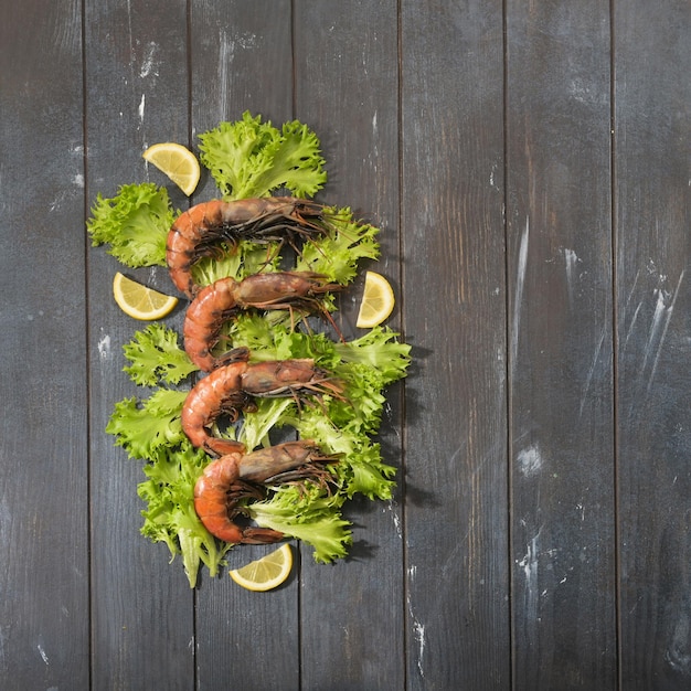 Raw shrimp are located on the leaves of green salad