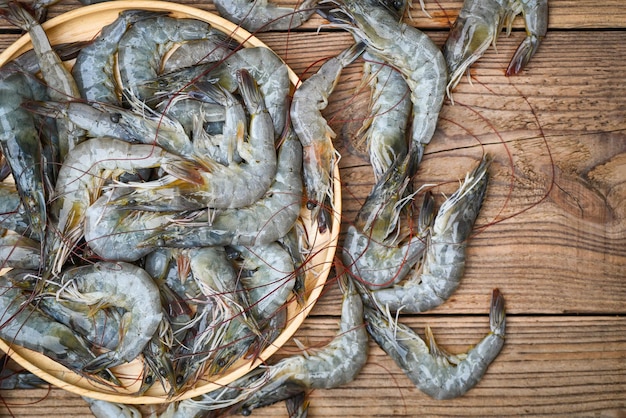 Raw shrimp on wooden plate and wooden board background for cooking close up fresh shrimps or prawns Seafood shelfish top view