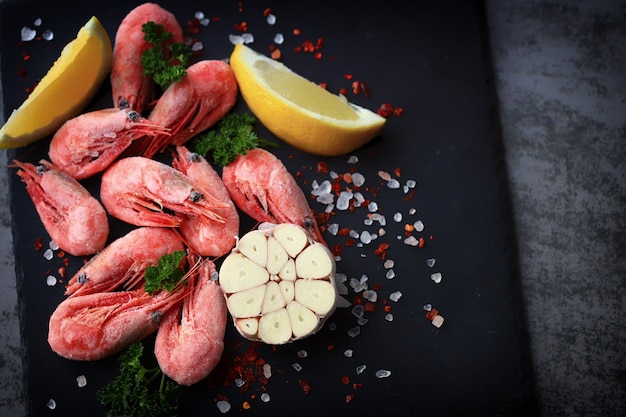 Raw shrimps with spices on a stone board