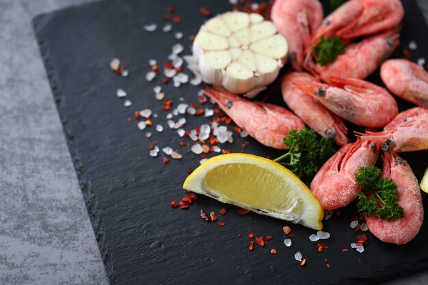 Raw shrimps with spices on a stone board