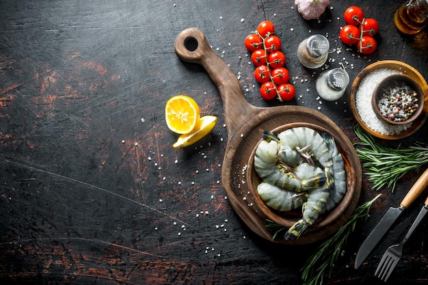 Raw shrimps with spices tomatoes on a branch and rosemary