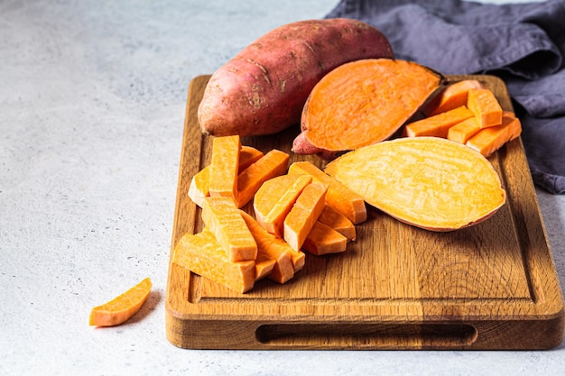 Raw sliced sweet potato on wooden board Cooking healthy food concept