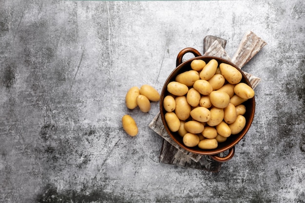 Raw small potatoes in a cast iron skillet on a beton background