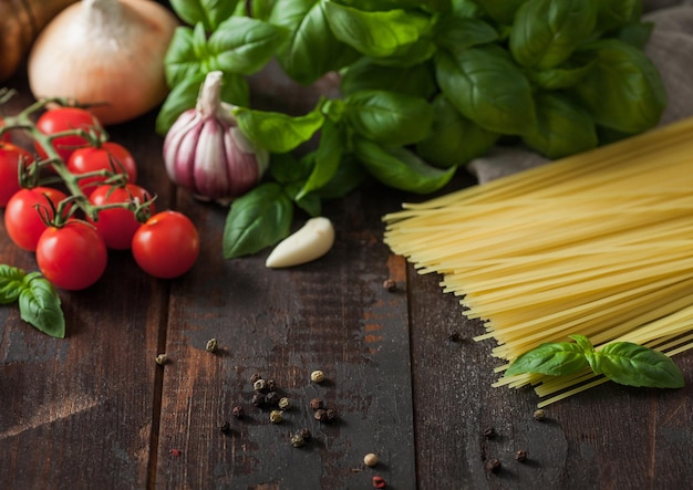 Raw spaghetti pasta in glass bowl with oil and garlic basil and tomatoes with pepper