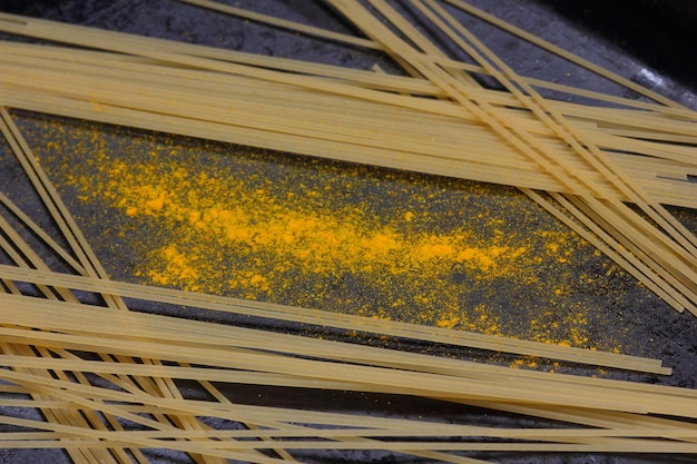 Raw spaghetti with yellow spices on a dark background Closeup of an Italian pasta View from above