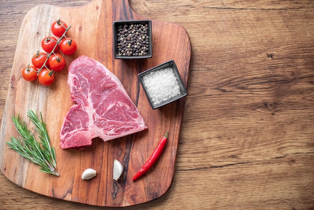 raw steak on a cutting board with herbs. Wooden background.