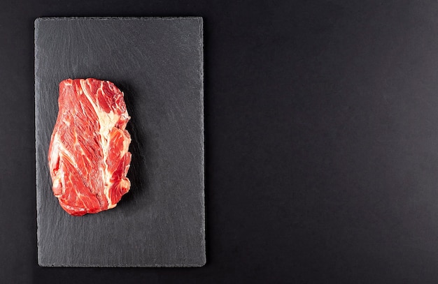 Raw steak meat on dark background copy space