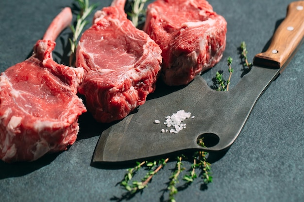 Raw steak with a meat cleaver on a dark stone background.