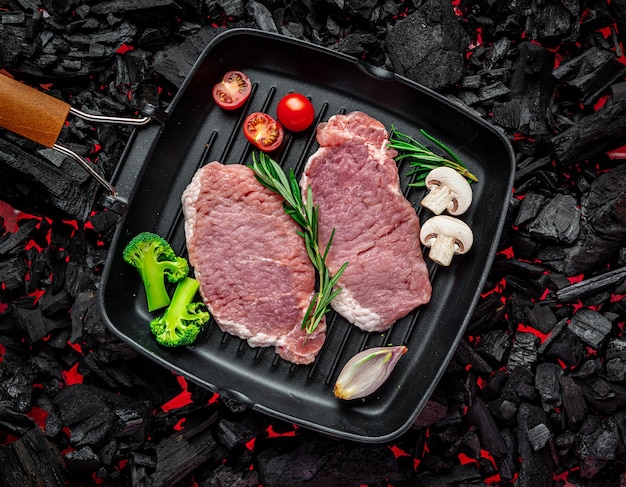 Raw steak with vegetables and herbs on a grill pan Organic meat