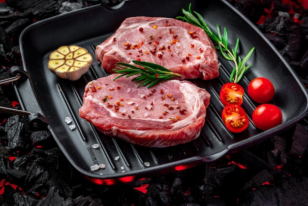 Raw steak with vegetables and herbs on a grill pan Organic meat