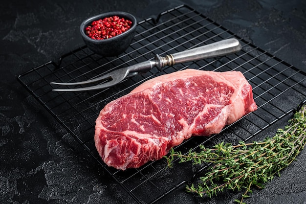 Raw striploin or New York beef meat steak ready for BBQ Black background Top view