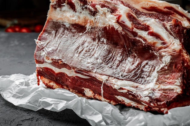 Raw T-bone steak cooking on stone dark table.