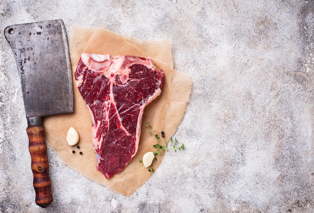 Raw T-bone steak with butchers knife