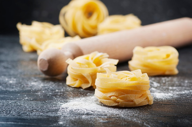 Raw tagliatelle nests on black table