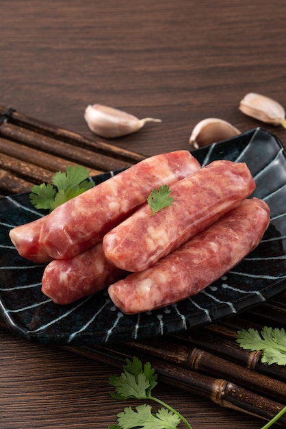 Raw Taiwanese sausage in garlic flavor in a plate on wooden table background