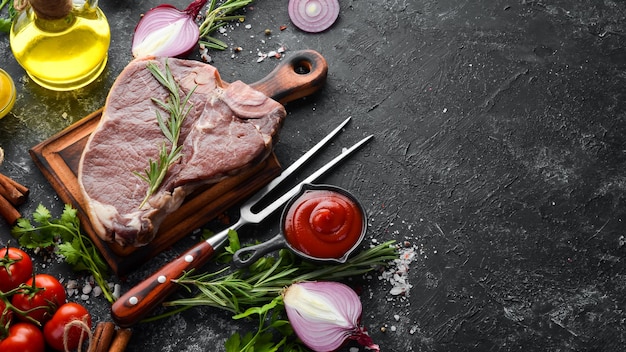 Raw Tbone steak on a black stone table Top view Free space for your text