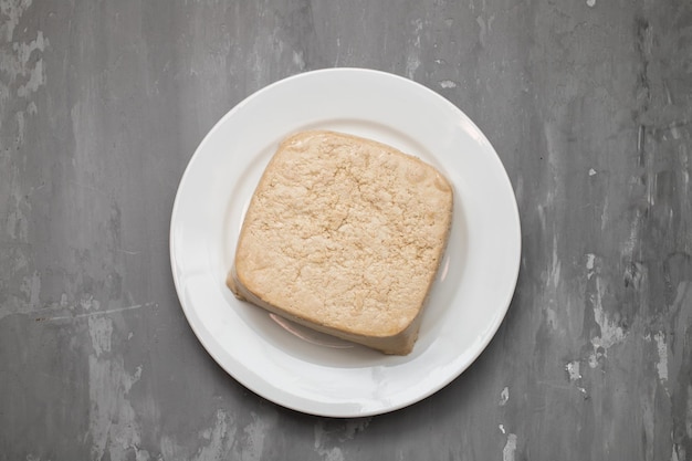 Raw tofu block on white small dish on ceramic