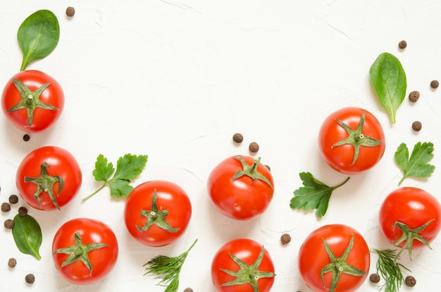 Raw tomatoes, herbs and black pepper on a light concrete background