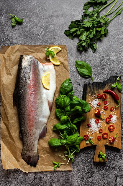 Raw trout fish on parchment Next to lemon spices and herbs for cooking