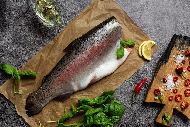 Raw trout fish on parchment Next to lemon spices and herbs for cooking