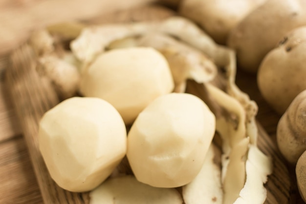 Raw tubers peeled potatoes on a wooden background