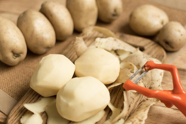 Raw tubers peeled potatoes on a wooden background