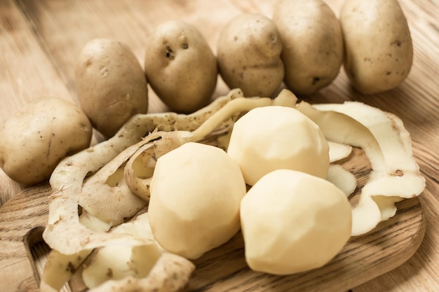 Raw tubers peeled potatoes on a wooden background