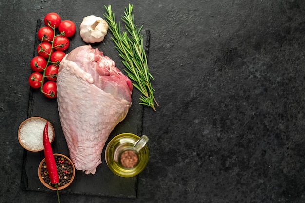 raw turkey leg with rosemary on stone table