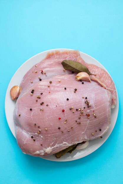 Raw turkey with black pepper and garlic on dish