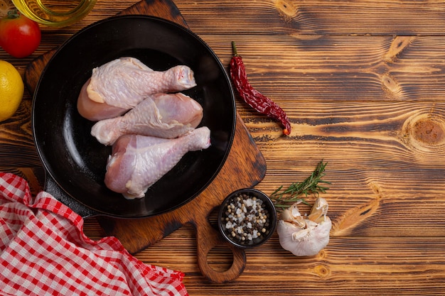 Raw uncooked chicken legs on the dark wooden surface.