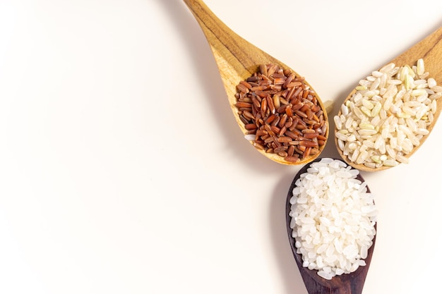 Raw and uncooked rice assortment in wooden spoon on white background Place for text Top view