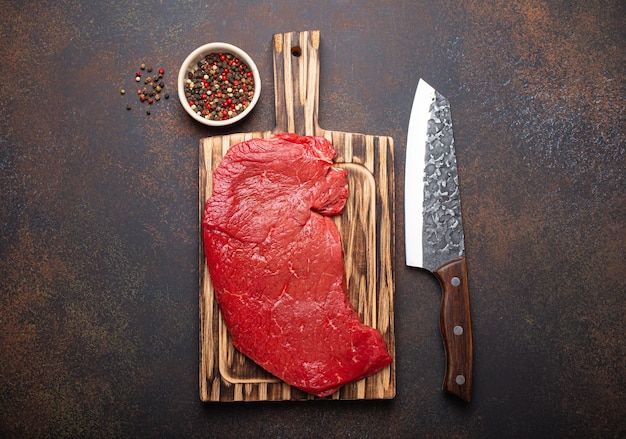 Raw uncooked top round beef steak on wooden cutting board