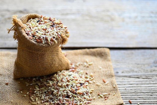 Raw various rice color mixed thai rice for cooking food brown rice in the sack with wooden background Loonzain rice brown black red white purple health food