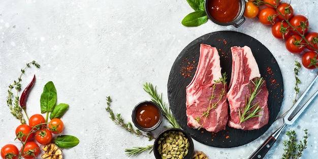 Raw veal steak on the bone on a black slate plate On a stone background