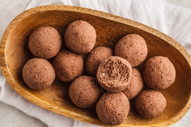 Raw vegan balls from nuts and cocoa in a wooden bowl, top view.