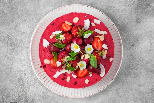 Raw vegan strawberry and cherry cashews cake with fresh berries nuts and flowers Veggie dessert Top view