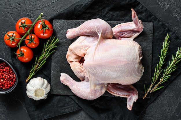 Raw whole chicken with rosemary and pepper