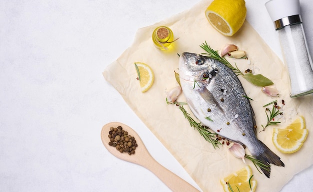 Raw whole dorado fish on white board and spices for cooking top view on white table