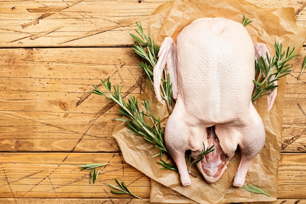 Photo raw whole duck pepper and rosemary wooden background top view copy space