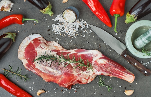 Raw, whole leg of lamb, shoulder of lamb, with spices, seasonings and herbs in the cooking process, top view