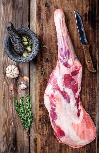 Photo raw whole leg of lamb with spices on a wooden board