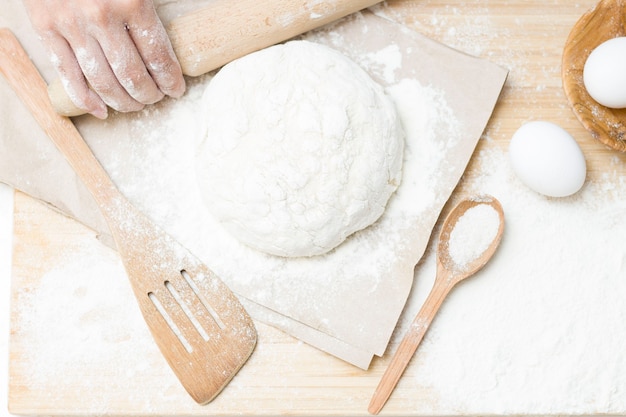 Raw yeast dough on a floured kitchen table, recipe idea. The concept of home baking or making dough. Rolling pin for dough