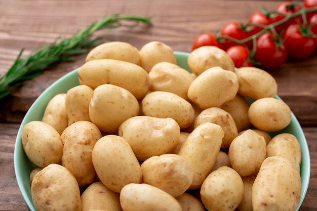 Raw young small potatoes on a wooden background.