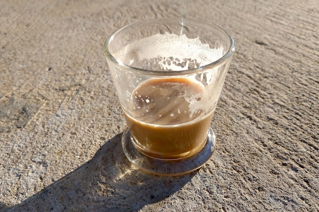 The rays of the sun fall on a transparent cup with fresh and tasty coffee