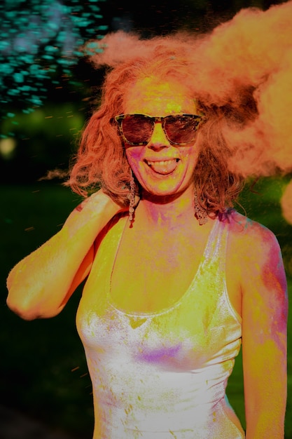 Re dhead woman having fun in a cloud of orange dry paint at the Holi colors festival