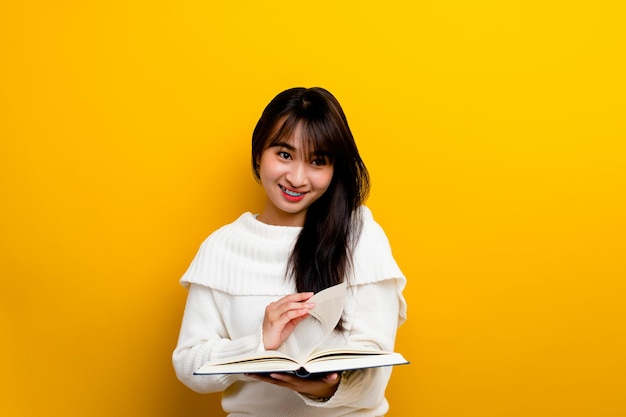 Read a book study with the protagonist seek knowledge food for thought girl reading a book and smiling in the photo studio yellow backdrop