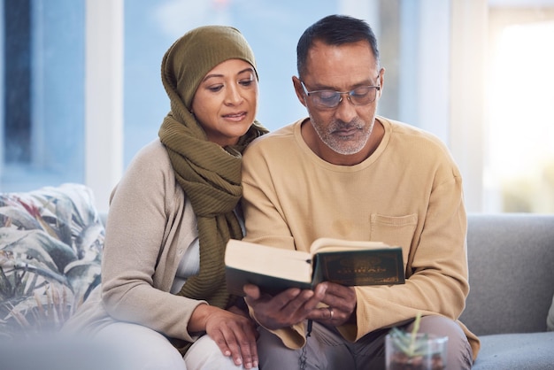 Reading book and eid mubarak with a muslim couple in the living room of their home together with the quran God Islam and ramadan with a man and woman bonding over religion in their house