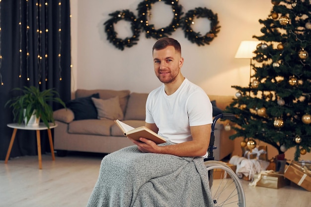 Reading the book New year is coming Disabled man in wheelchair is at home