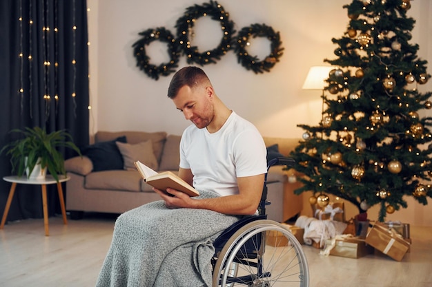 Reading the book New year is coming Disabled man in wheelchair is at home