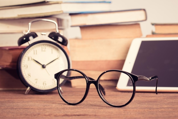 reading eye glasses on wooden table and old book background